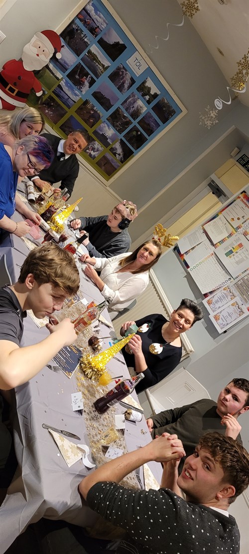 Students And Staff Sat Around The Christmas Dinner Day Table