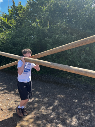 NES NCS Student Carrying Wooden Beams For Boat