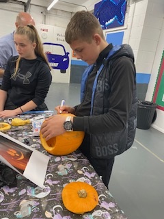Male Student Drawing On Pumpkin