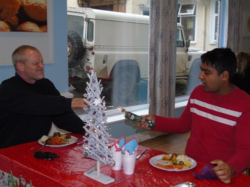 Student And Staff Enjoying Christmas Dinner And Pulling Cracker