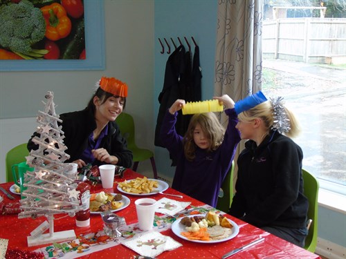 Student Enjoying Christmas Dinner With Two Female Staff Members