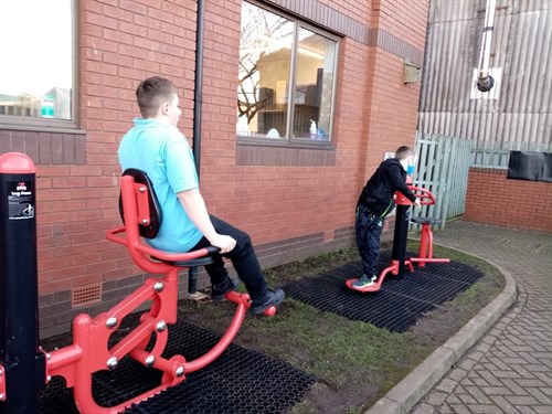 Two Male Students Using Outside Gym Equipment