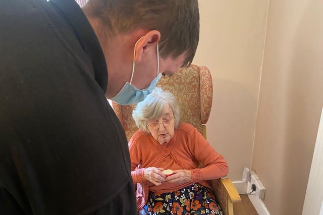 Student Offering Cake To A Lady In A Care Home